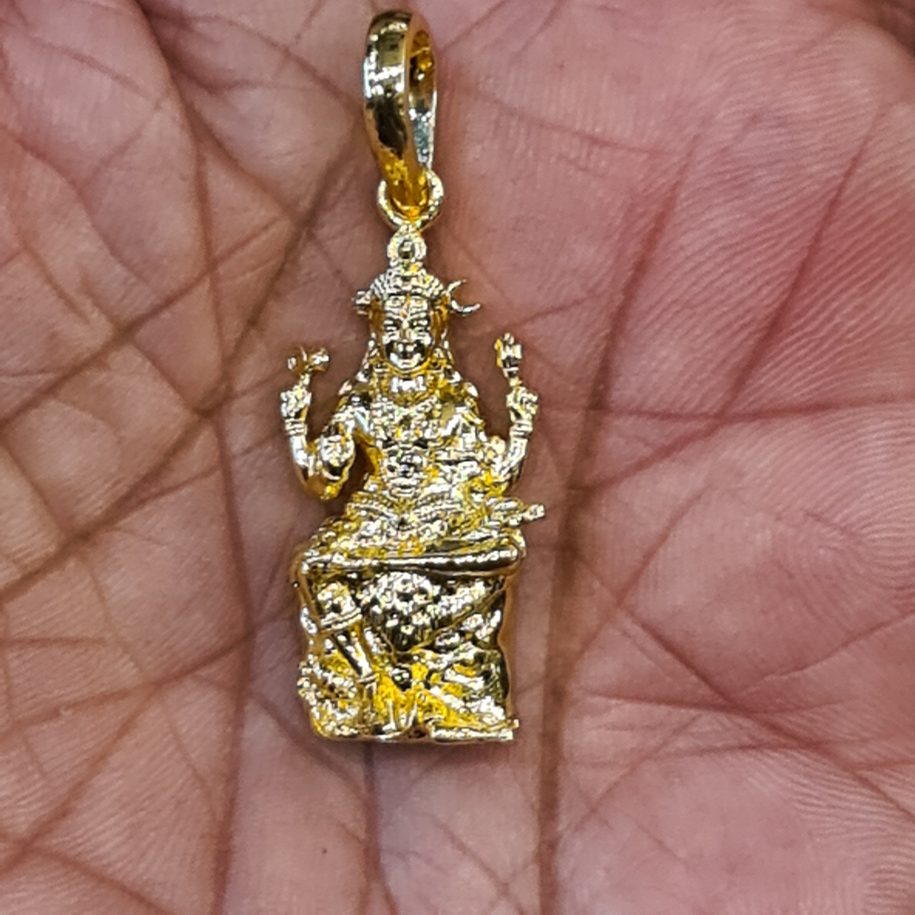 Panchaloham Dakshinamurthy pendant held in hand showing gold finish and intricate seated deity detailing
