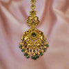 Decorative gold pendant with green stones on a pink fabric background