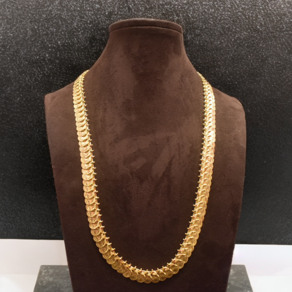 Gold chain necklace on a brown velvet mannequin against a black background