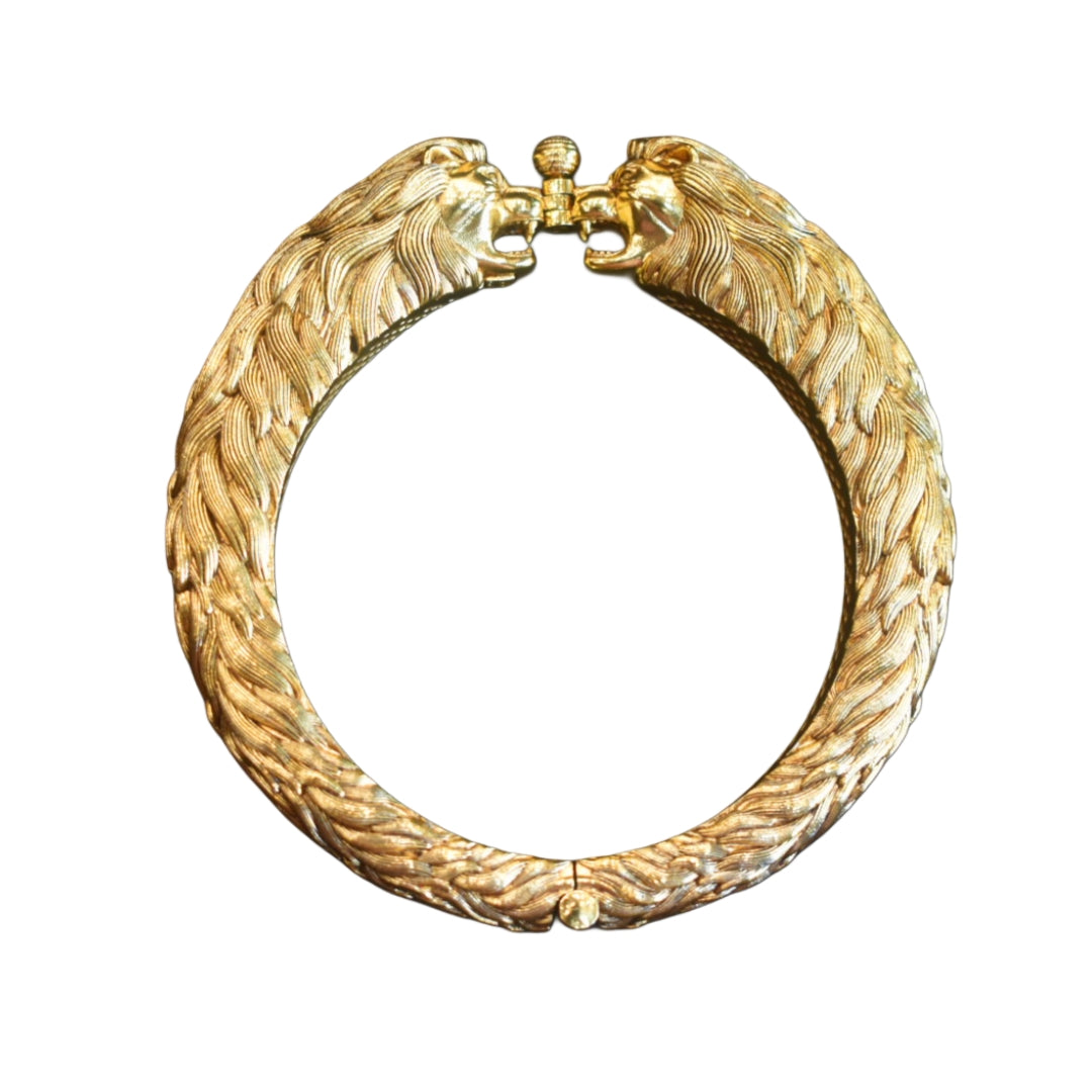 Gold bracelet with lion head designs on a white background
