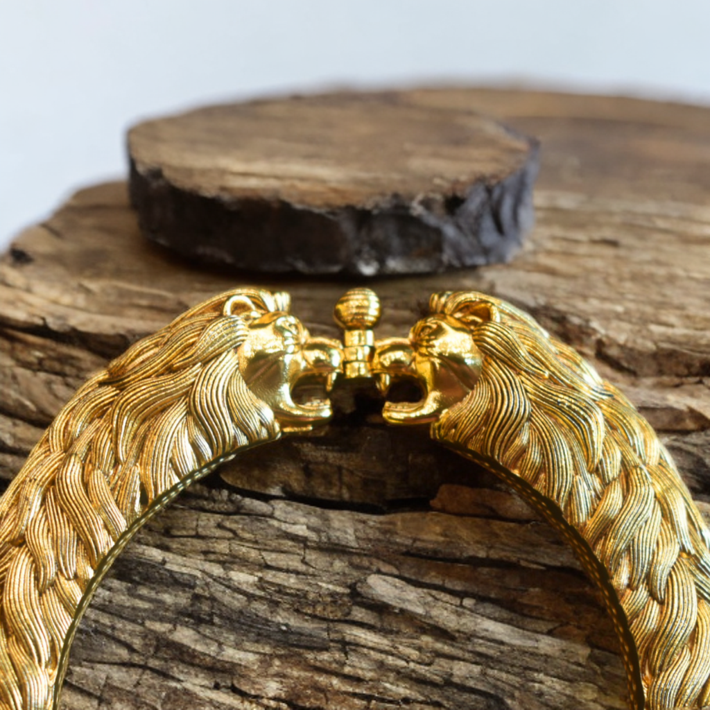 Gold bracelet with lion head design on a wooden surface