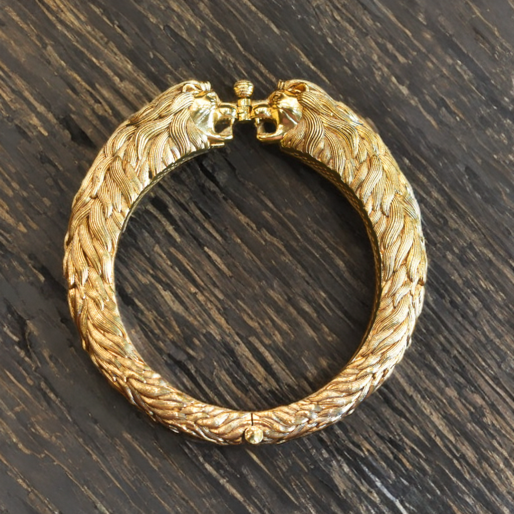 Gold bracelet with intricate design on a dark wooden surface