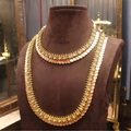 Gold necklace on a brown mannequin bust with a reflective background