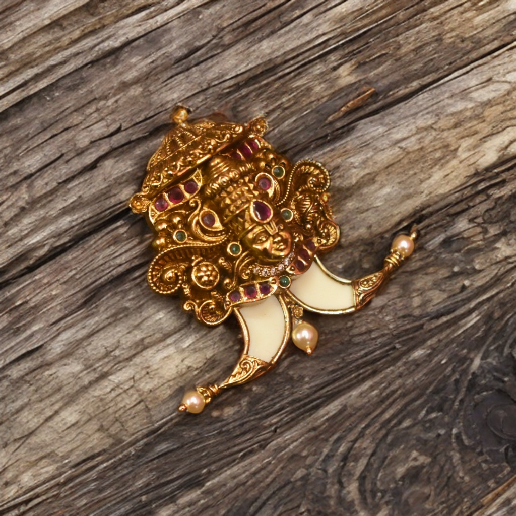 Decorative brooch with gold and gemstone details on a wooden surface