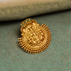 Gold decorative element with green gemstones on a textured green surface