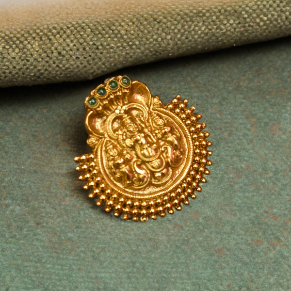 Gold decorative element with green gemstones on a textured green surface