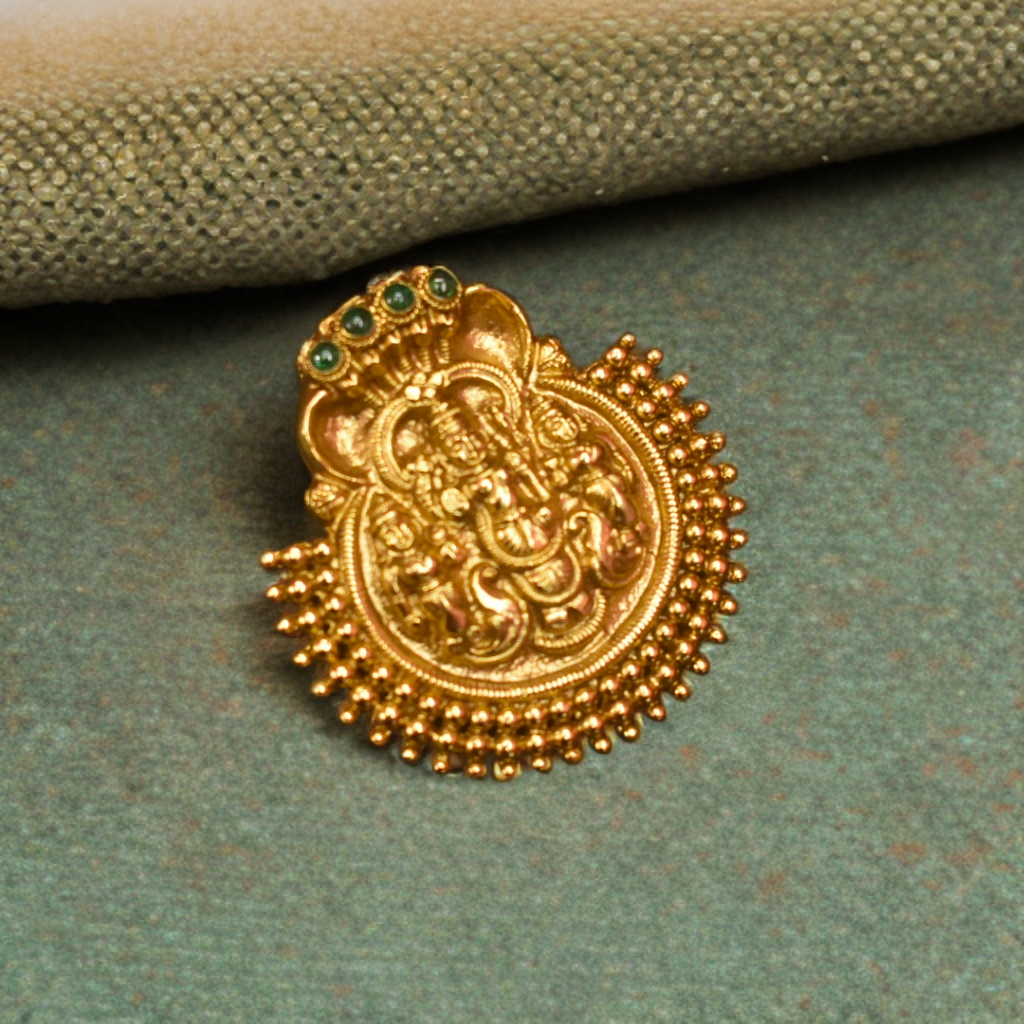 Gold decorative element with green gemstones on a textured green surface