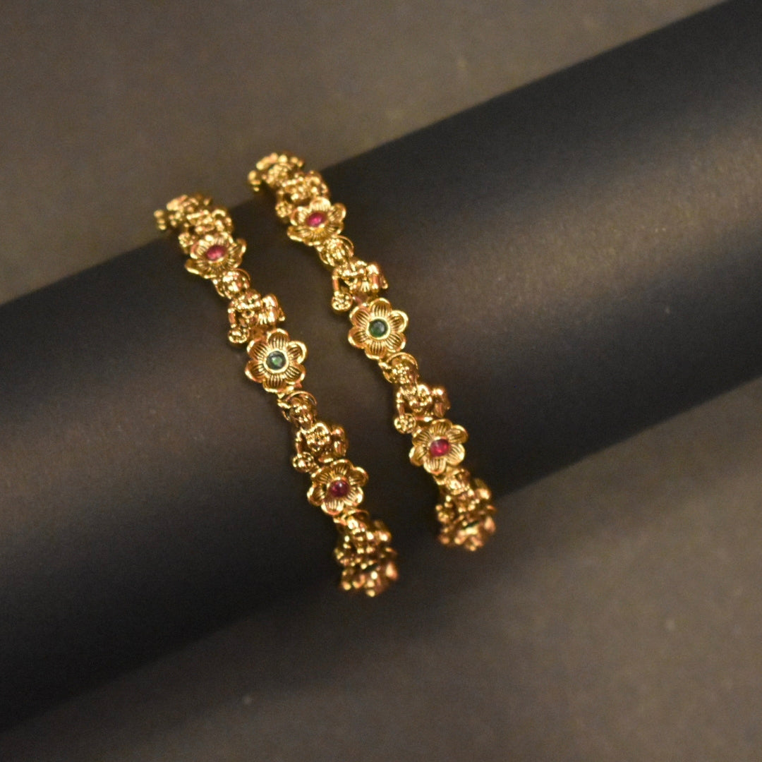 Gold Bangles with gemstones on a dark surface