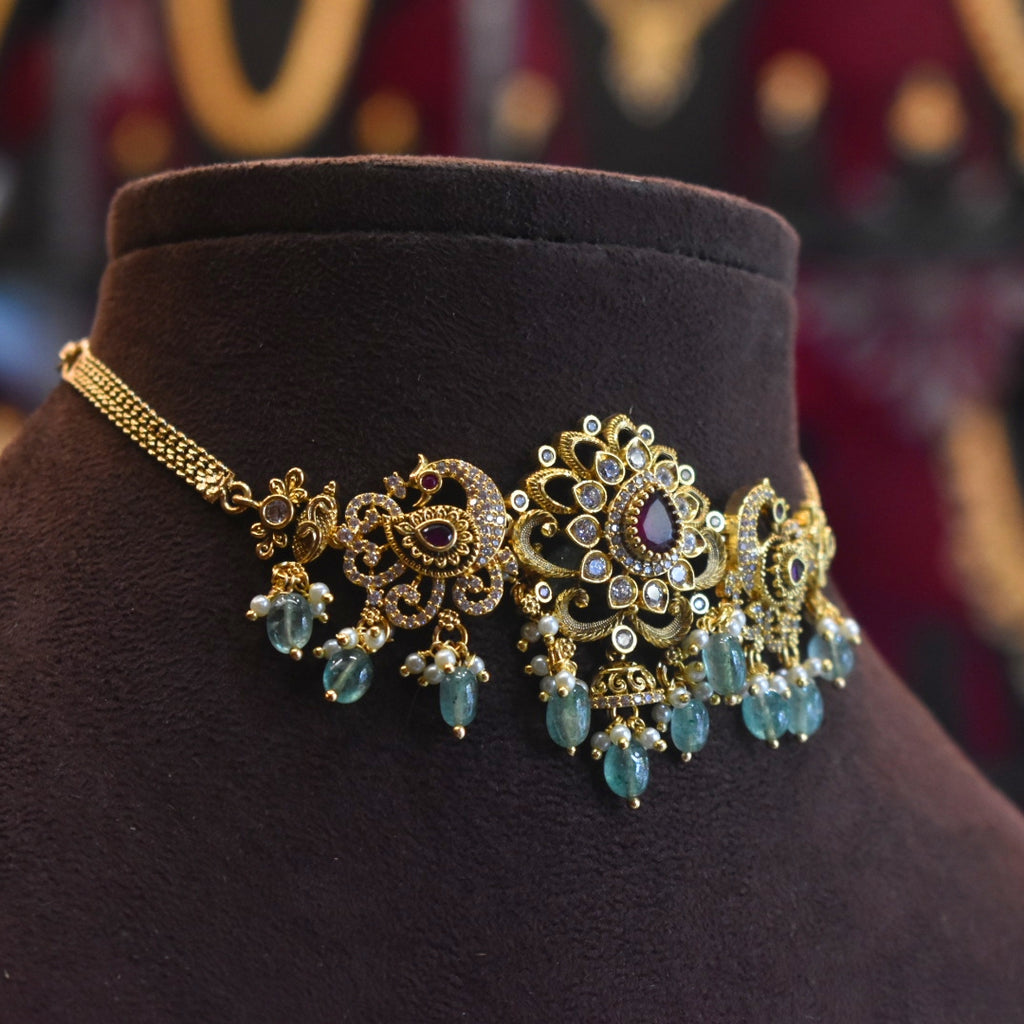 Ornate gold and blue gemstone necklace on a dark brown mannequin bust.