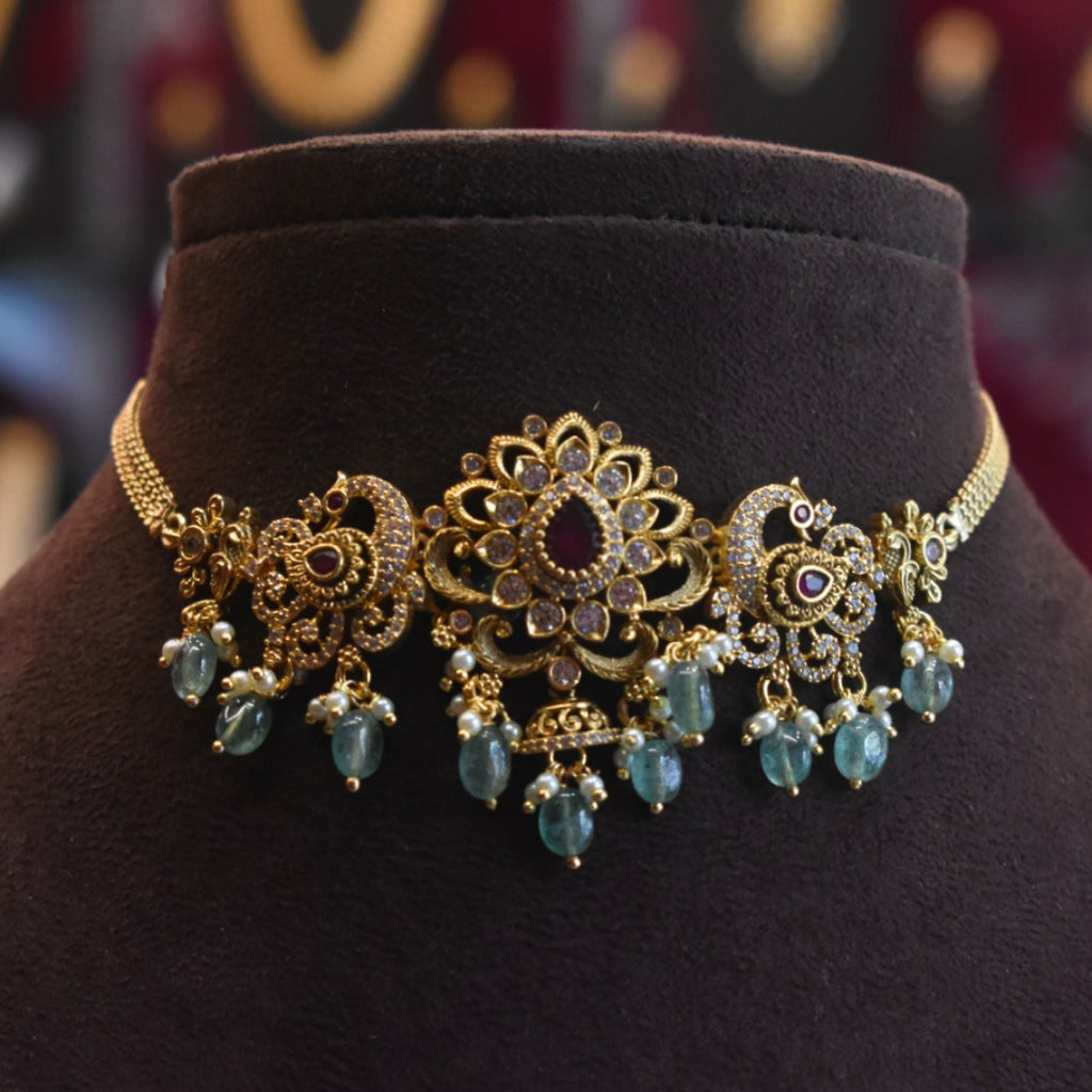 Ornate gold and turquoise necklace on a dark brown mannequin