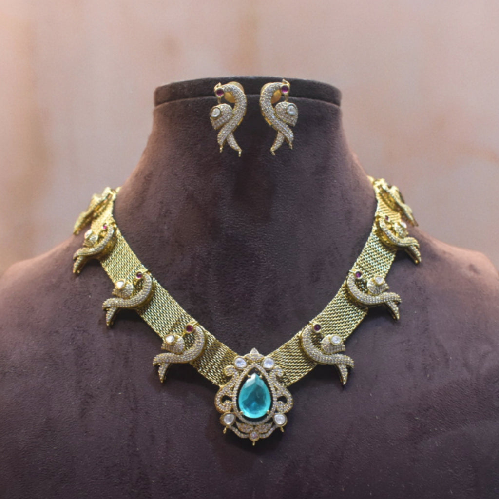 Gold necklace with a blue gemstone and matching earrings on a mannequin.