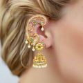Close-up of a person wearing an ornate gold earring with pearls and gemstones.