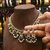 Gold and blue jewelry set on a mannequin bust with a hand holding an earring.