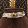 Decorative choker with beads and gemstone on a brown mannequin against a patterned background