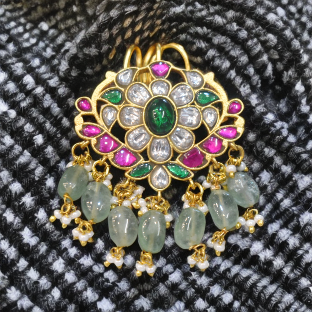 Decorative pendant with gemstones on a textured fabric background