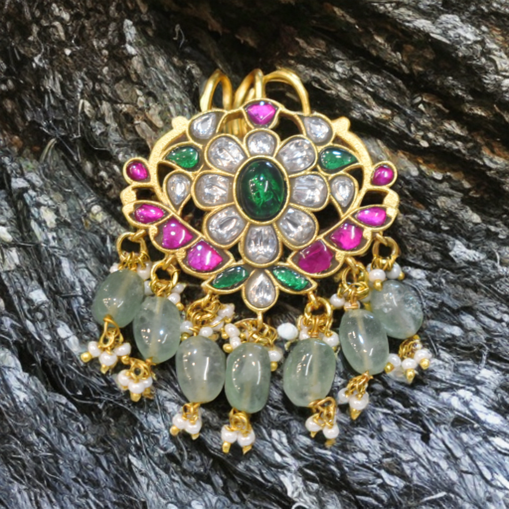 Decorative pendant with gemstones and beads on a textured surface