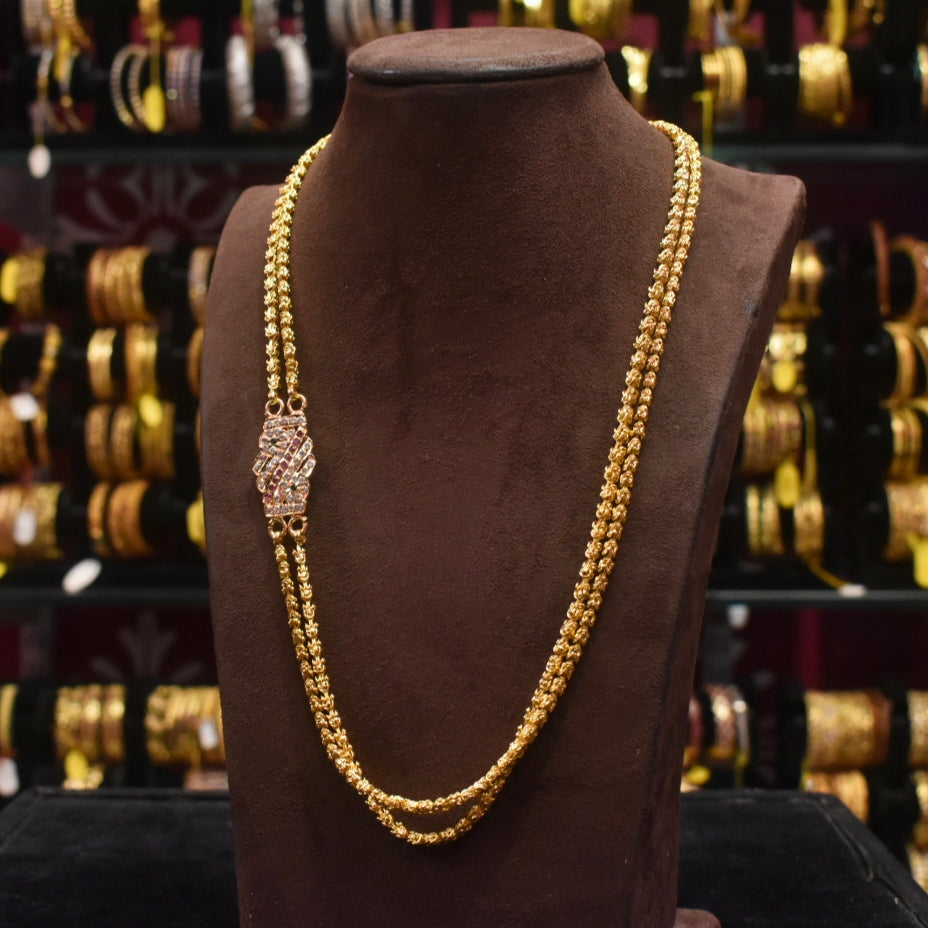 Gold necklace on a mannequin bust with a blurred background of gold bracelets.