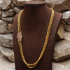 Gold necklace on a brown mannequin against a stone wall background