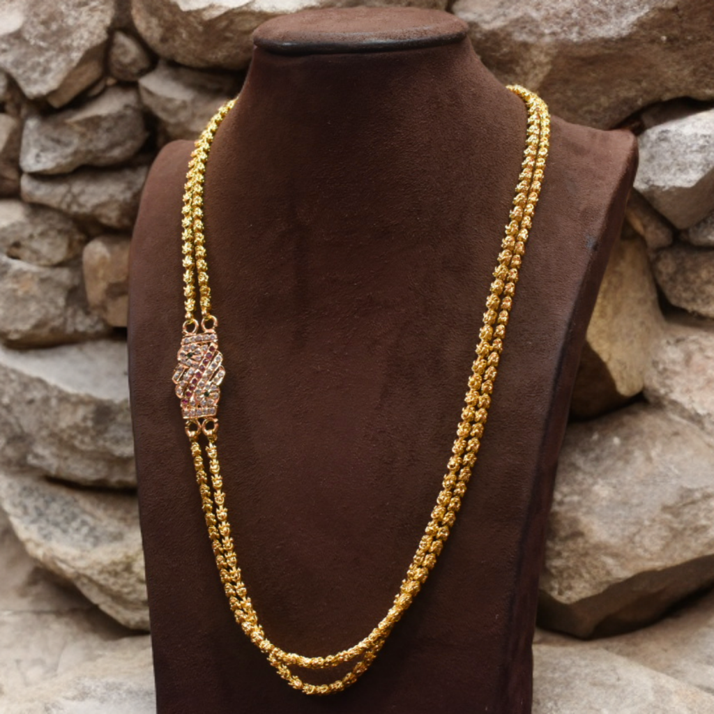 Gold necklace on a brown mannequin against a stone wall background