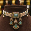 Decorative necklace with green gemstones and pearl-like strands on a brown stand.