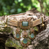 Ornate necklace with green stones on a textured surface