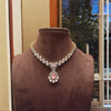 Elegant necklace with a pink gemstone on a brown mannequin against a neutral background
