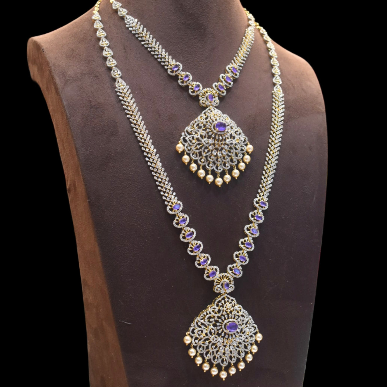 Ornate necklace with purple gemstones on a mannequin bust against a black background