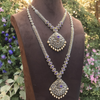 Ornate necklace on a mannequin with a floral background