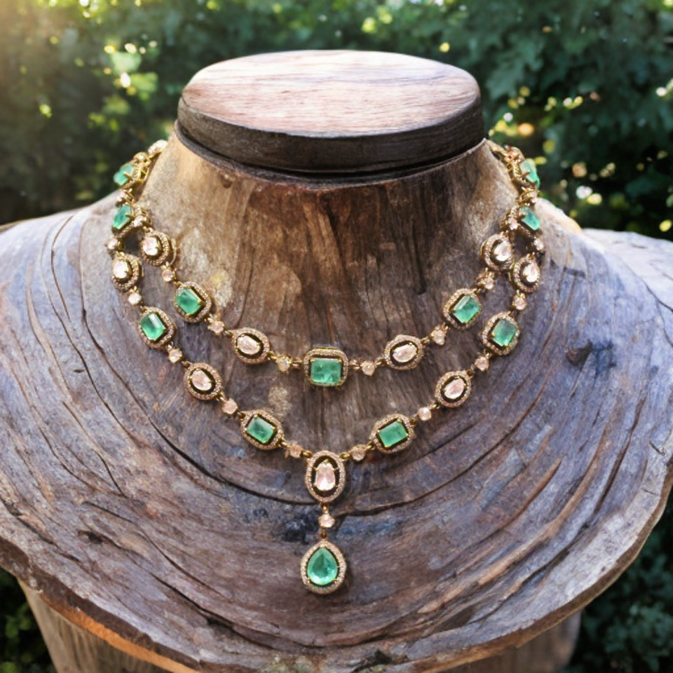 Ornate necklace with emerald stones on a wooden mannequin against a natural background