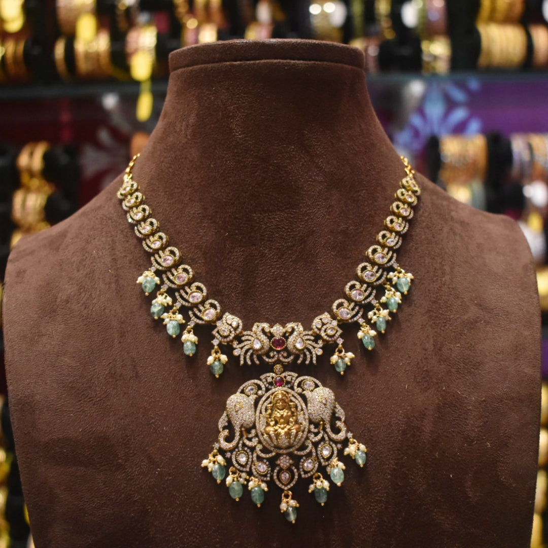 Ornate gold necklace with green gemstones on a brown mannequin