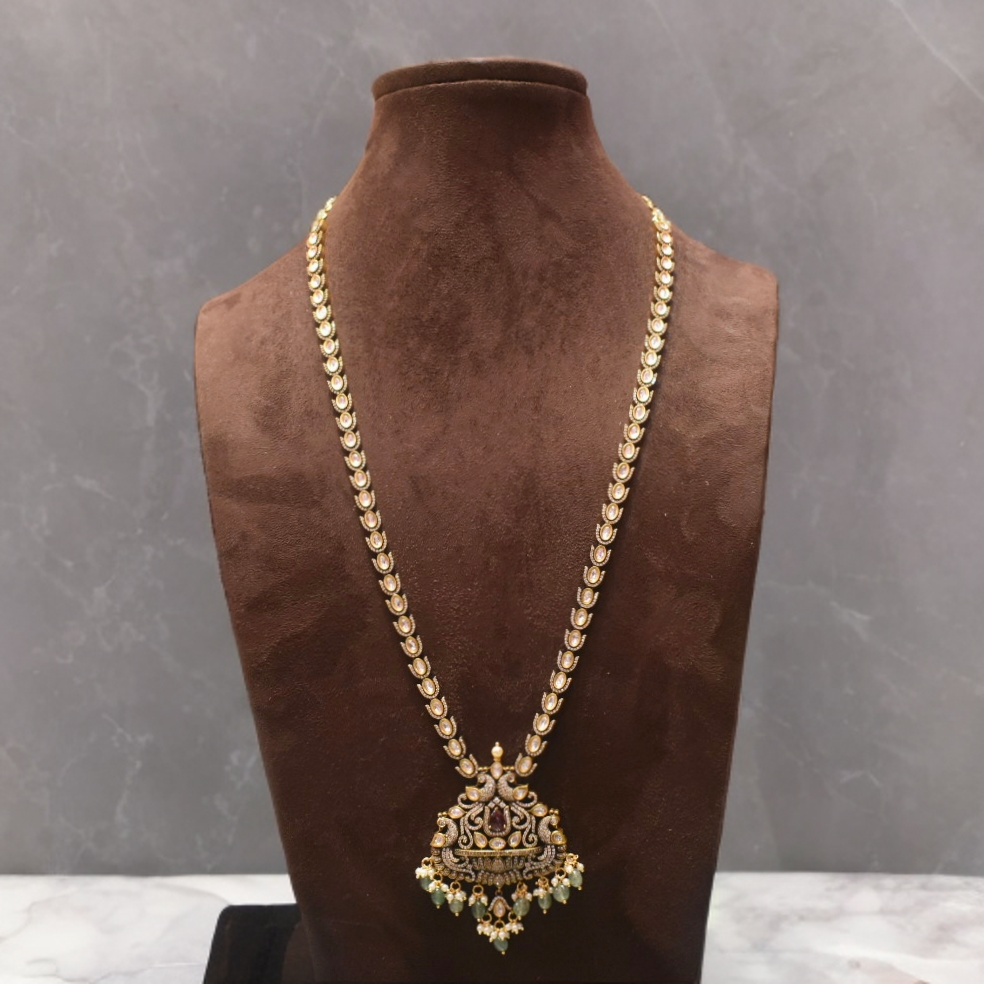 Gold necklace with a pendant on a brown velvet stand against a gray background