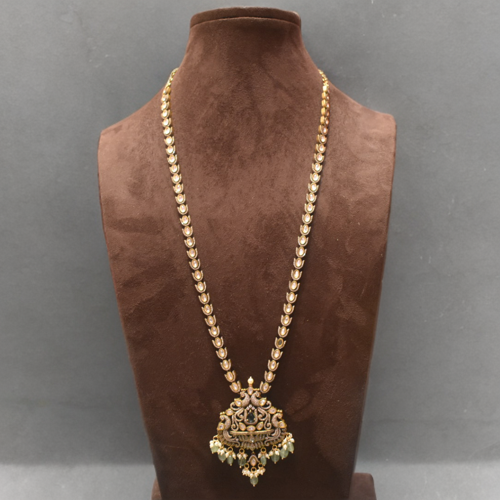Gold necklace with a pendant on a brown velvet mannequin against a gray background