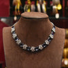 Necklace with floral designs on a brown mannequin bust against a blurred jewelry store background.