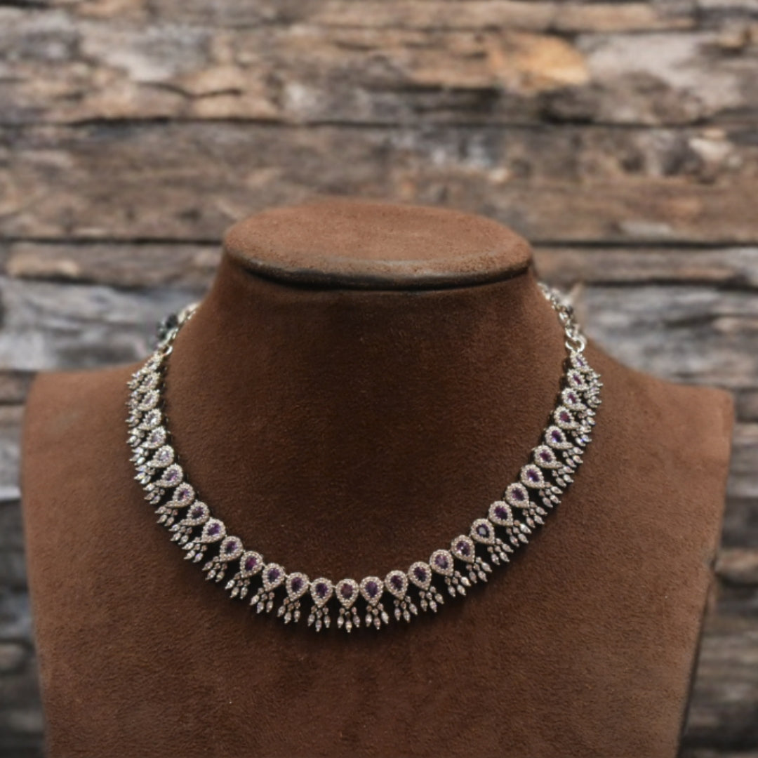 Necklace on a brown velvet stand with a rustic stone wall background