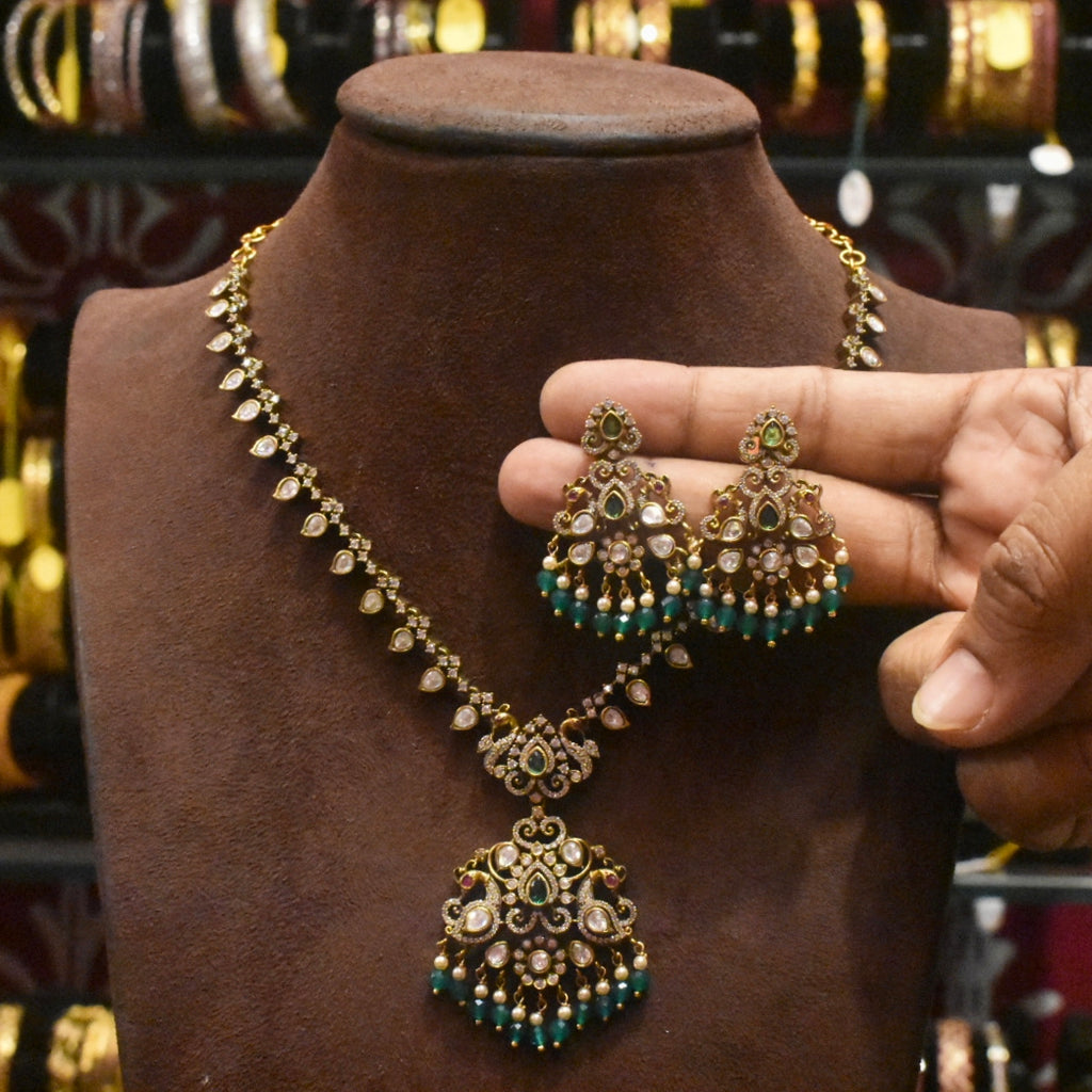 Jewelry set with necklace and earrings on a mannequin bust, held by a hand.
