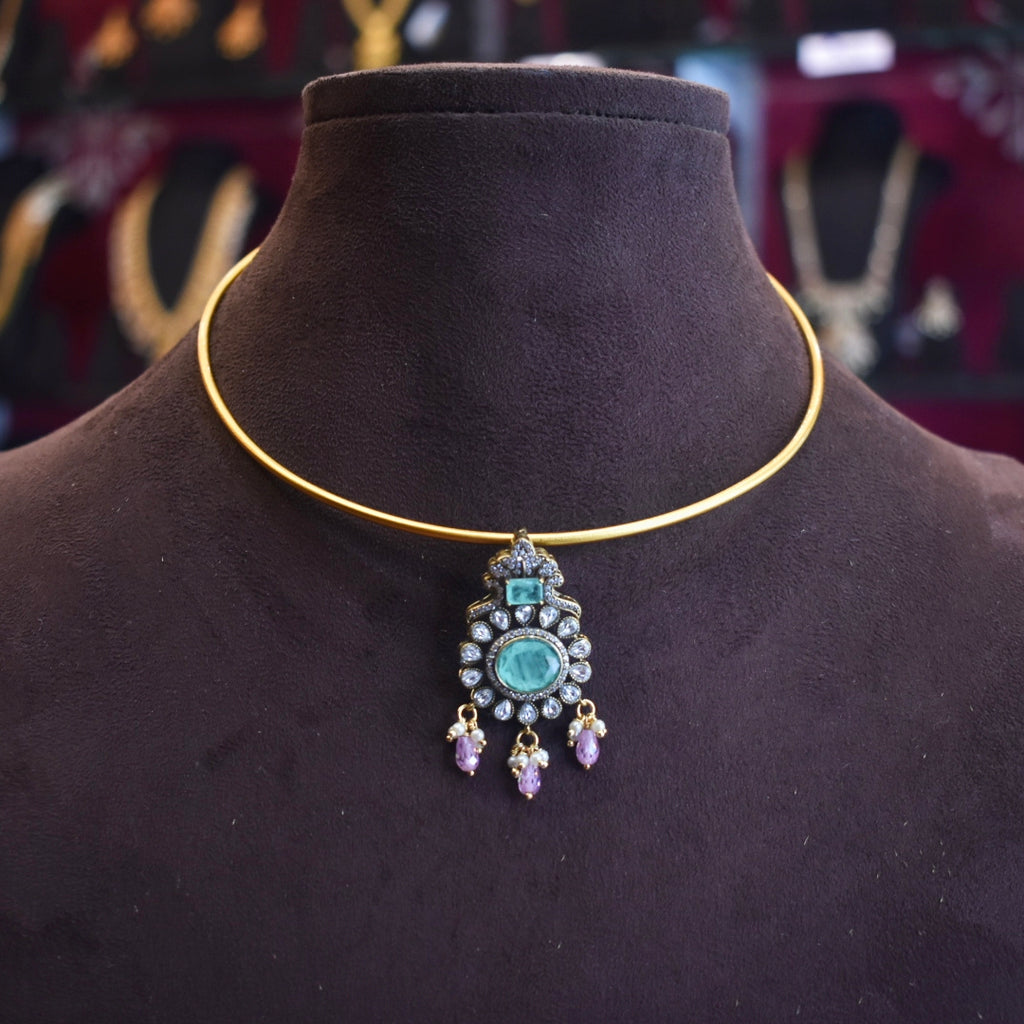 Gold necklace with a decorative pendant on a black mannequin
