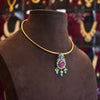 Gold necklace with a pendant on a brown mannequin bust against a blurred jewelry store background.
