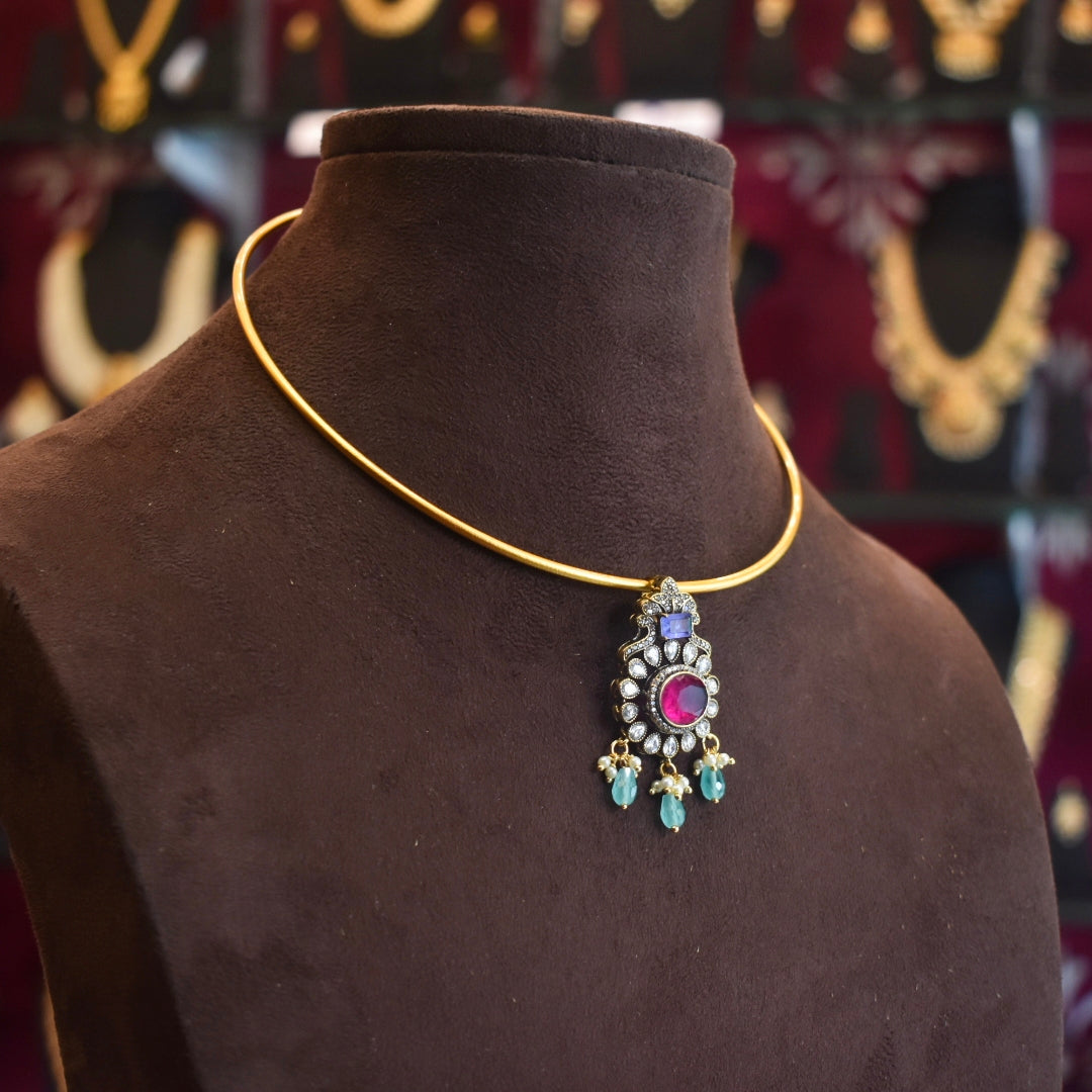 Gold necklace with a pendant on a brown mannequin bust against a blurred jewelry store background.
