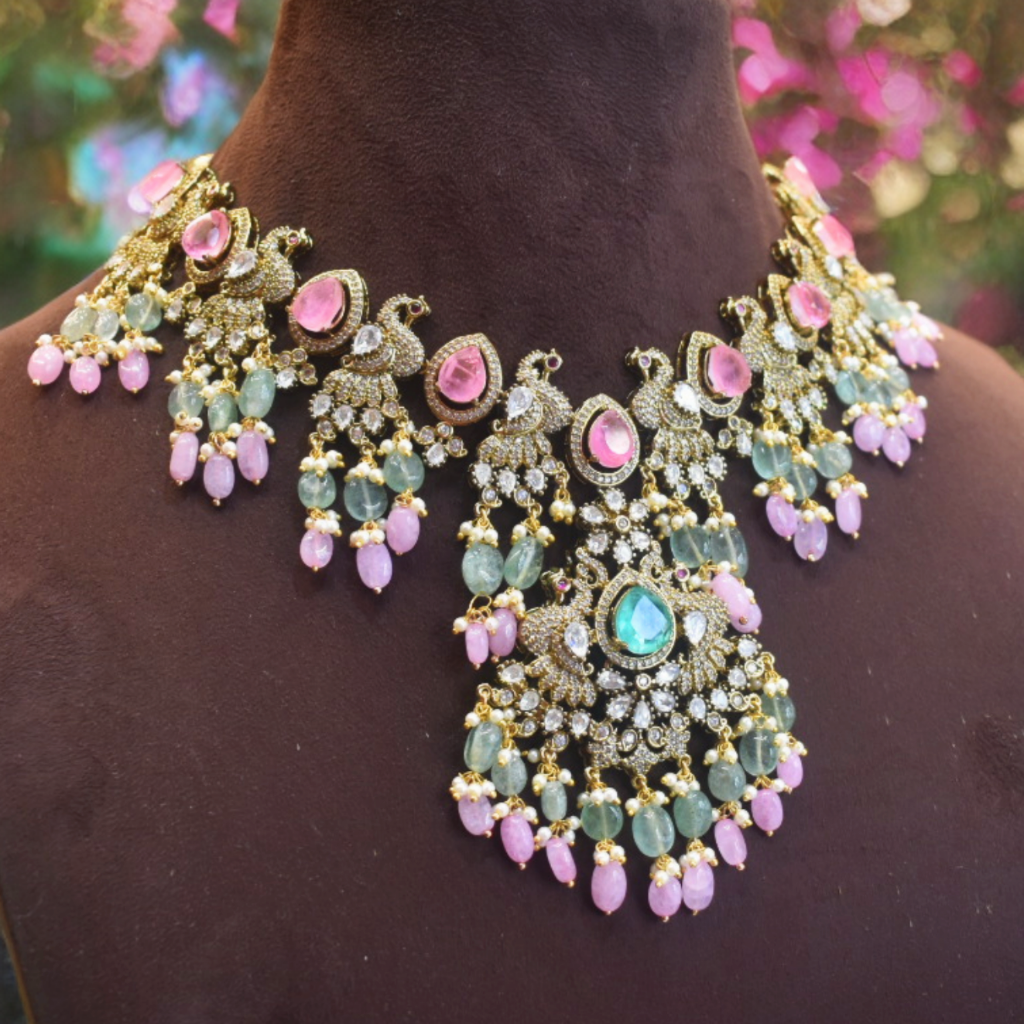 Ornate necklace with pink and green stones on a mannequin against a blurred floral background