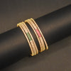 Gold bangles with embedded stones on a black rod against a dark background