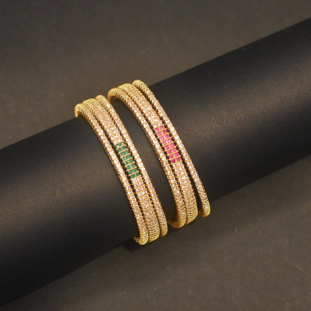 Gold bangles with embedded stones on a black rod against a dark background