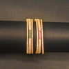 Gold bangles with gemstone inlays on a black rod against a dark background