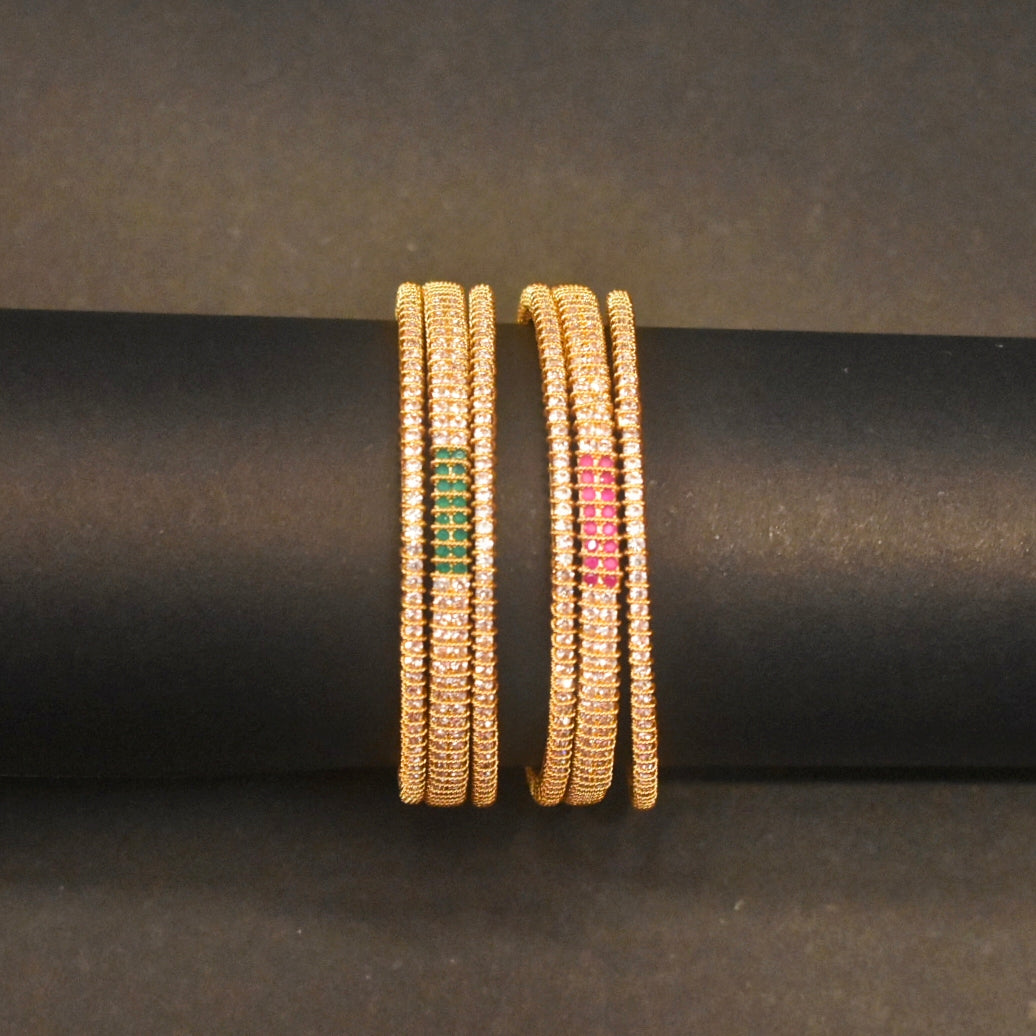 Gold bangles with gemstone inlays on a black rod against a dark background
