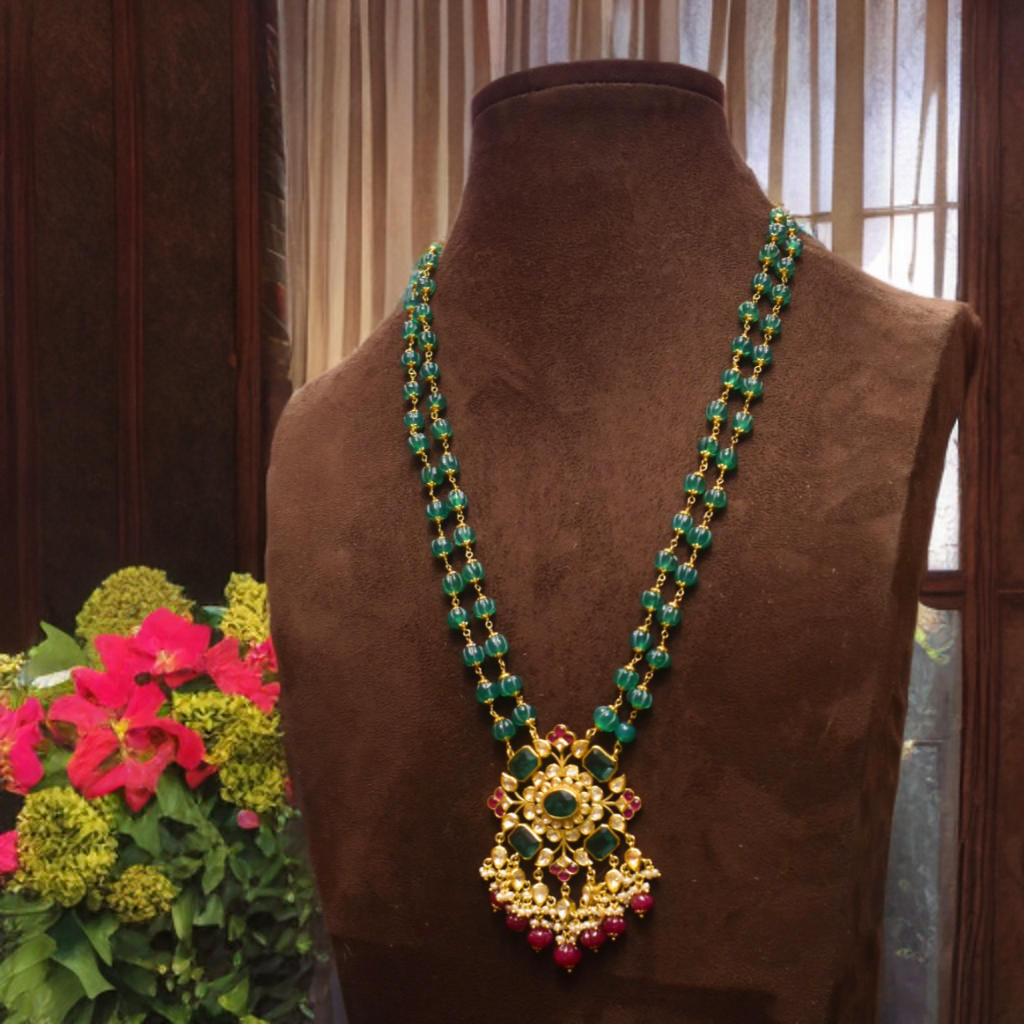 Decorative necklace on a brown mannequin with flowers in the background