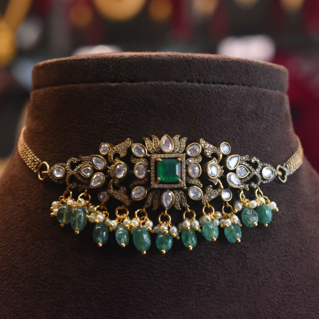 Decorative necklace with emeralds and gold on a brown velvet stand