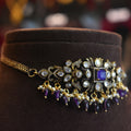 Decorative necklace with purple and gold elements on a brown velvet cushion