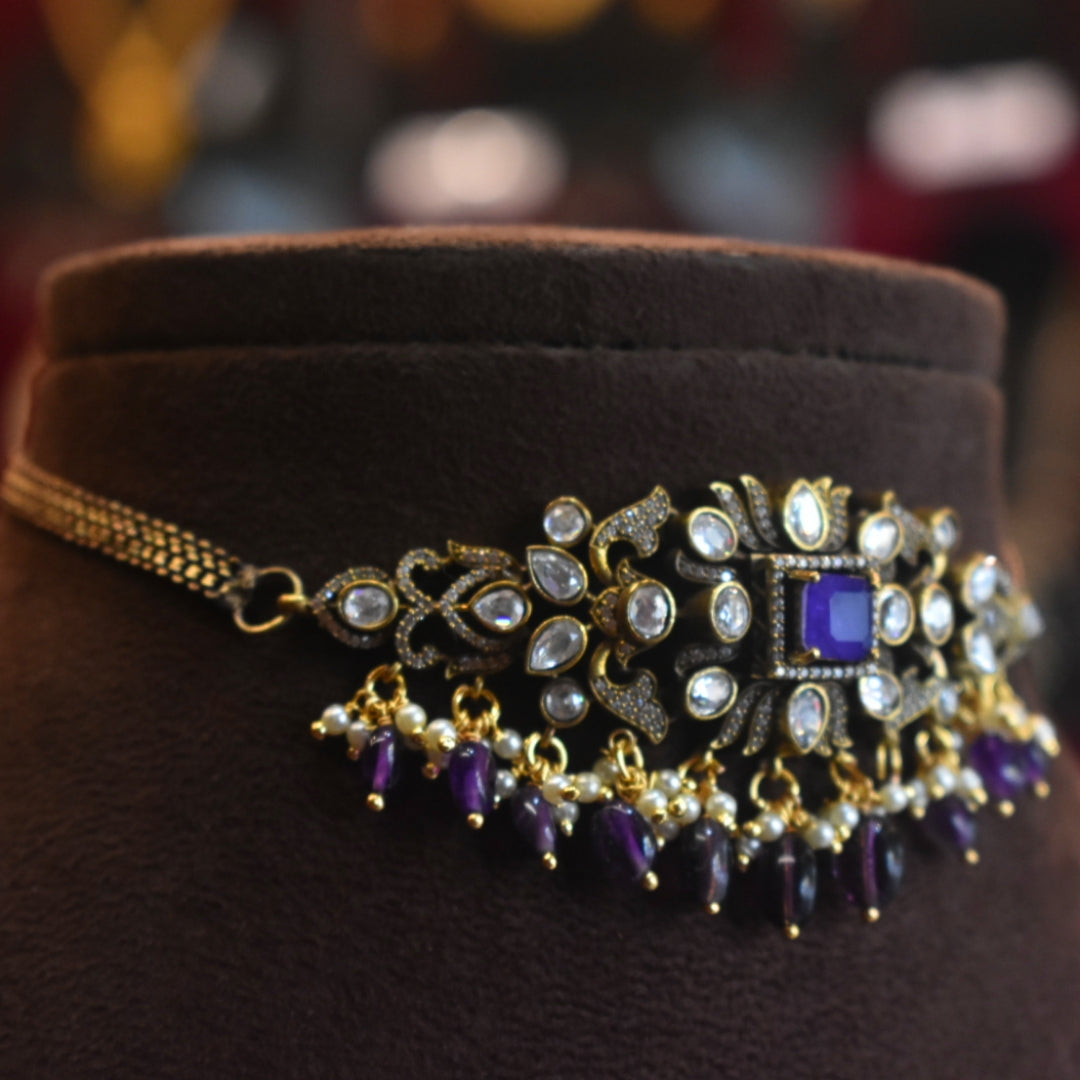 Decorative necklace with purple and gold elements on a brown velvet cushion