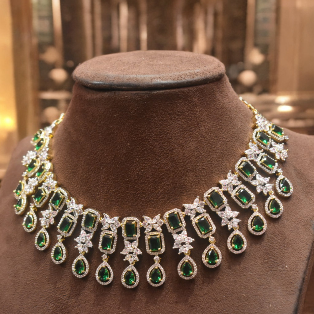 Elegant necklace with green gemstones and white stones on a brown velvet stand.