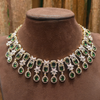 Green and white gemstone necklace on a brown velvet mannequin