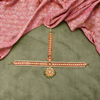 Decorative jewelry set on a green fabric background with a pink fabric draped above.